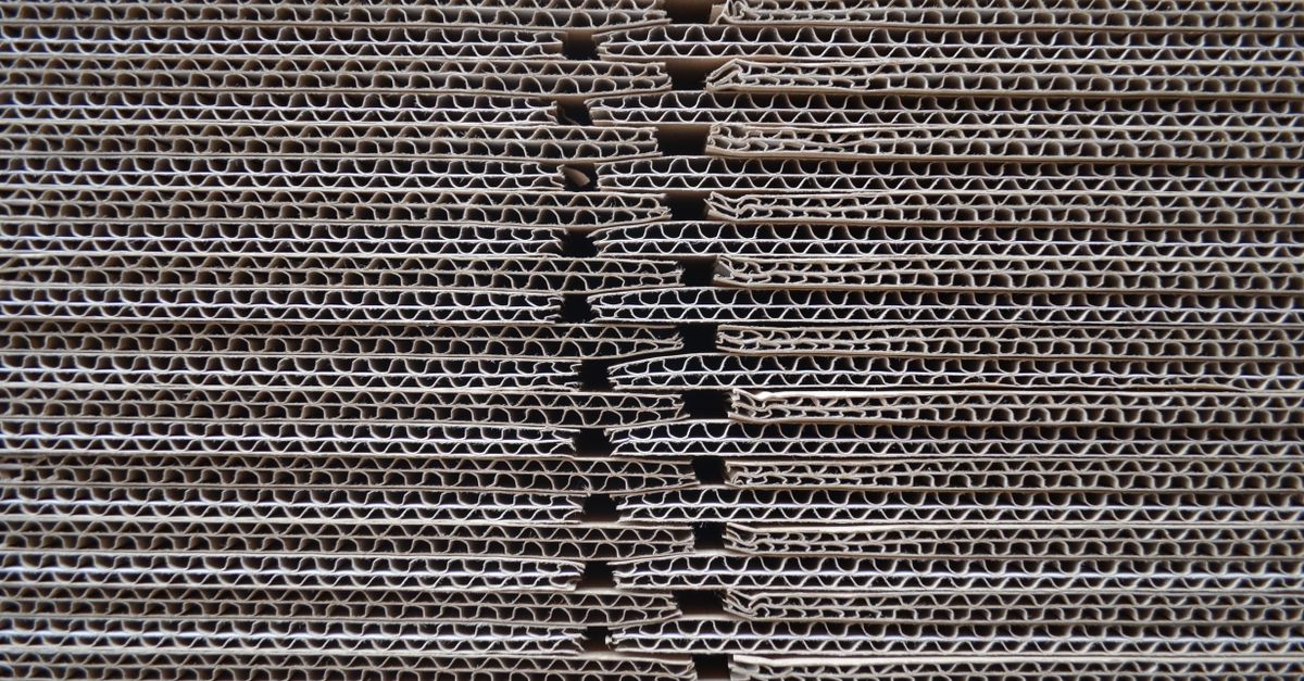 Corrugated cardboard stacked and seen edge-on, showing the wavy flutes between the flat paper liners
