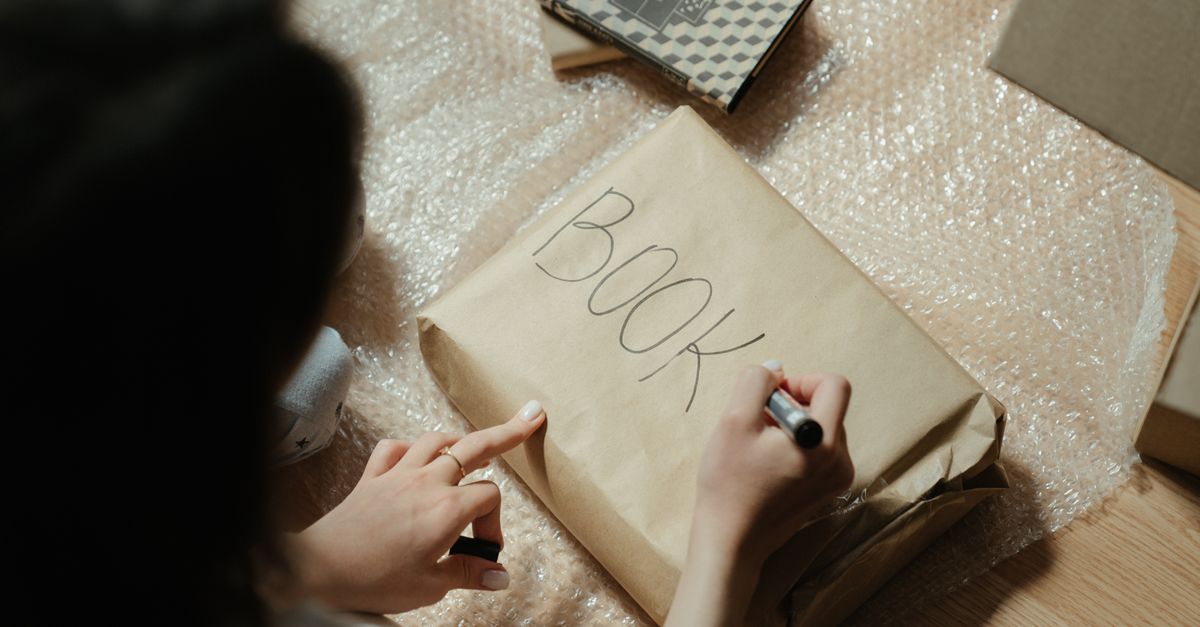 Book packaging: a book wrapped in brown kraft paper and marked BOOK in pen, resting on bubble wrap